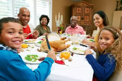 Happy family gathered around the table for a Thanksgiving meal.