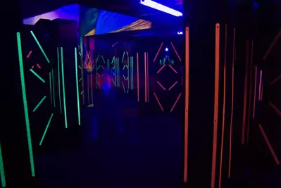 The colorful florescent lights of a laser game room with a blurred laser player.